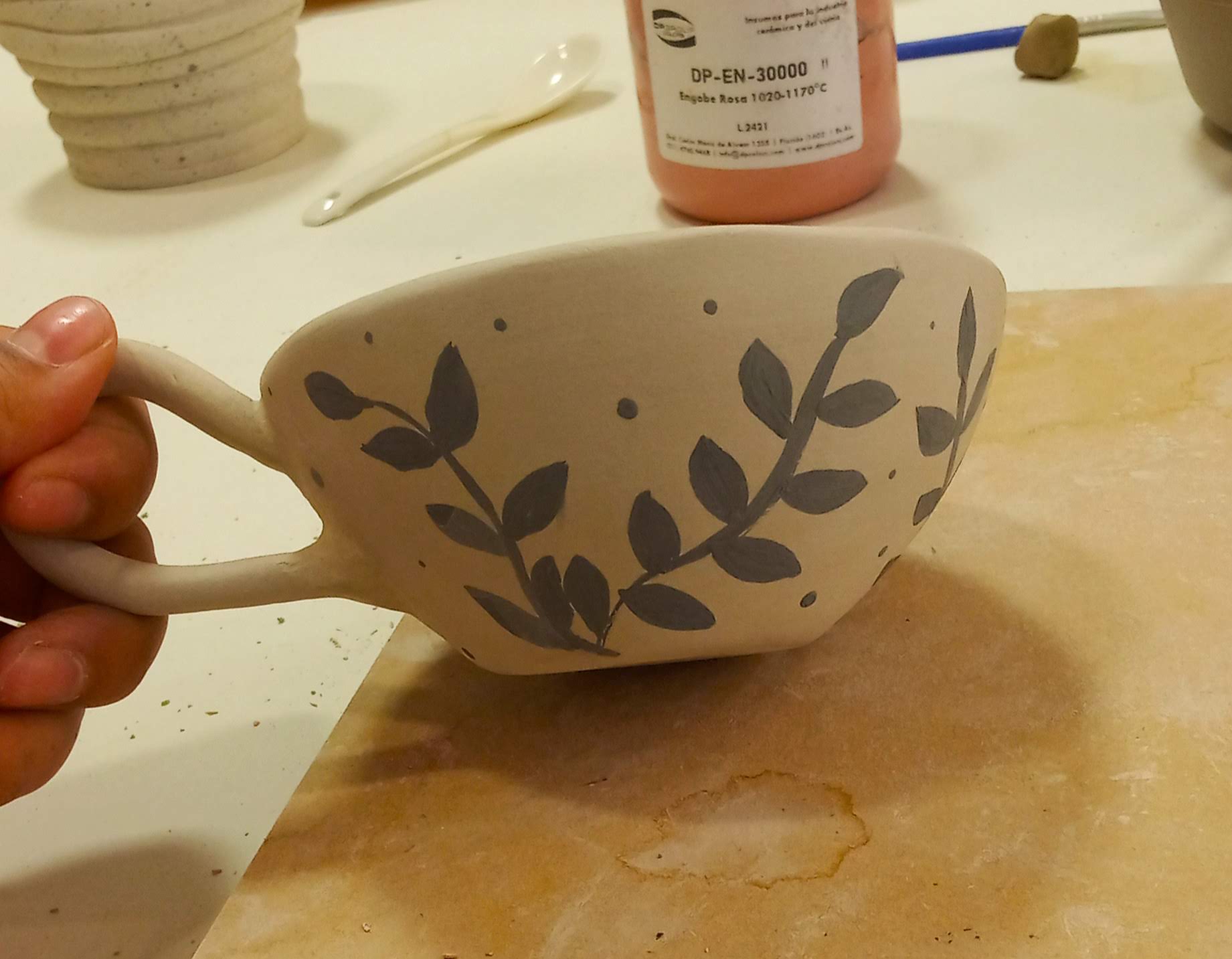 Taza baja con aza grande, hecha a mano decorada con engobe negro en forma de hojas pequeñas